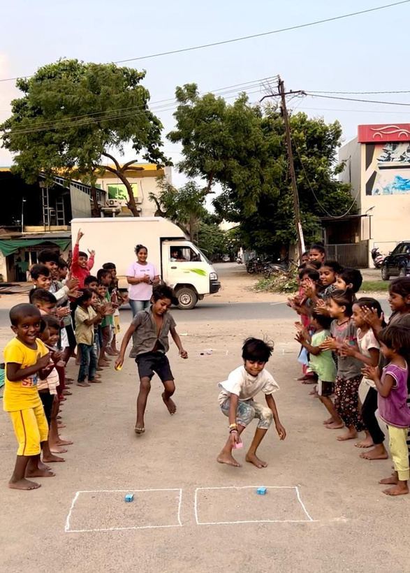 Children cheering as others run a race on the street.