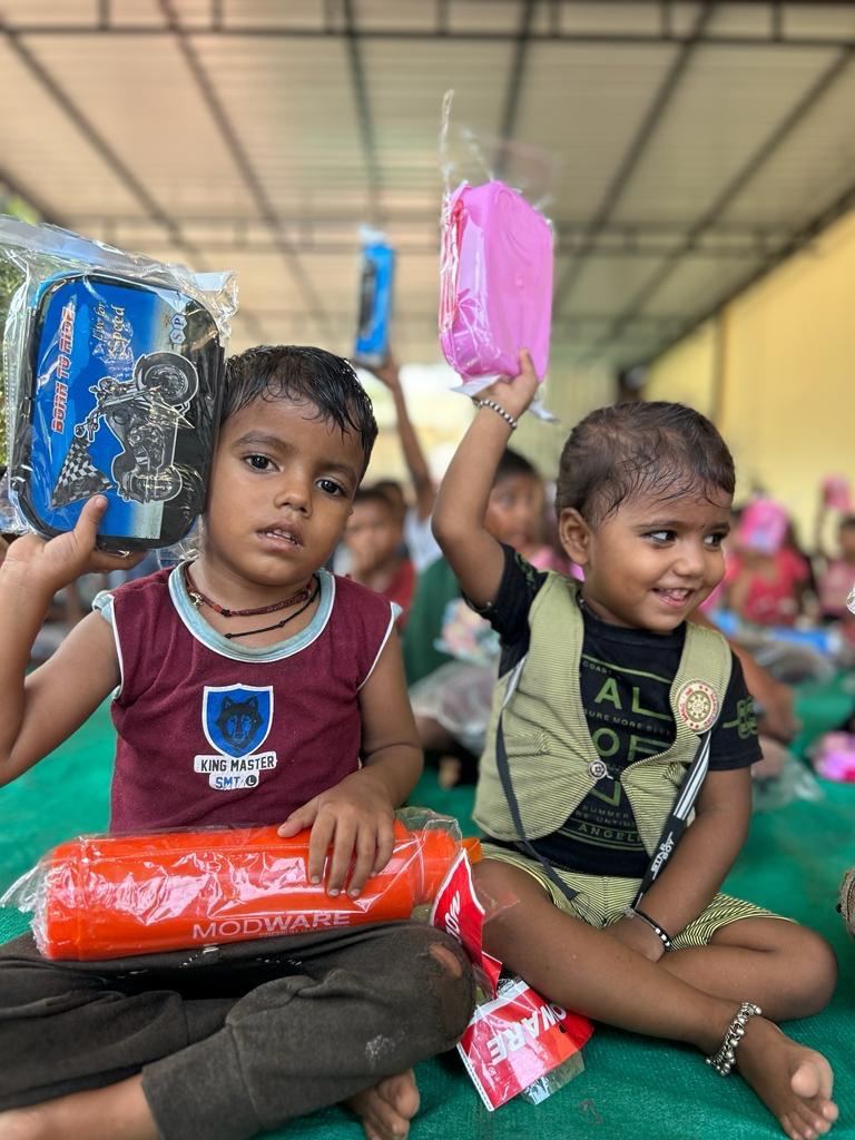 Two young boys smiling and holding up new school kits.