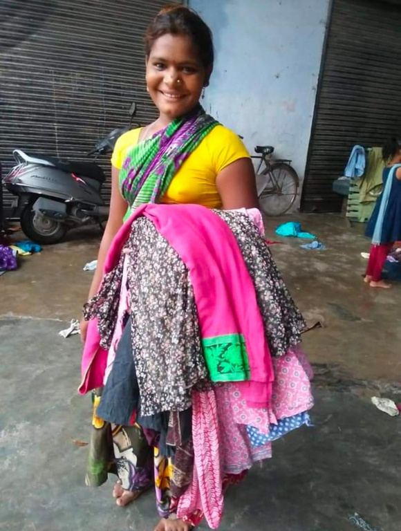 A woman carrying a bundle of colourful clothes.