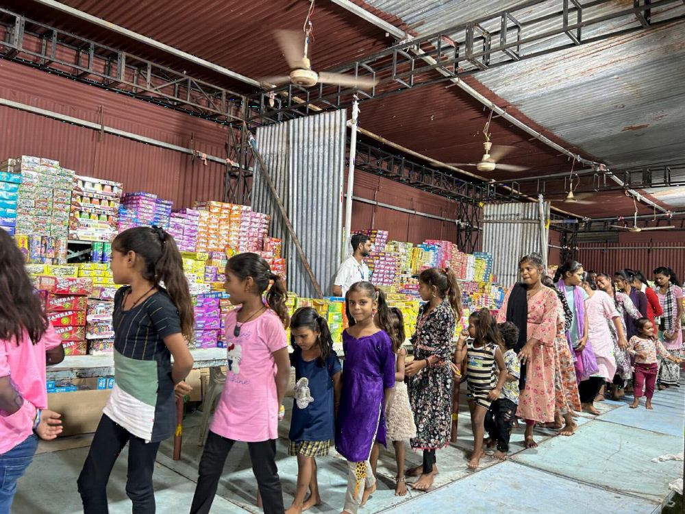 Children lined up in a hall stocked with festive gift boxes.