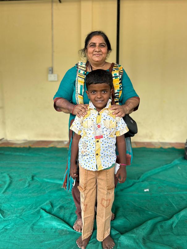 A woman standing behind a young boy with her hands on his shoulders.