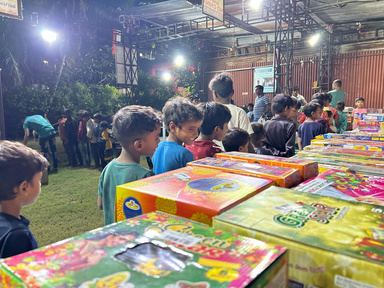 Children lined up in a hall stocked with festive gift boxes.