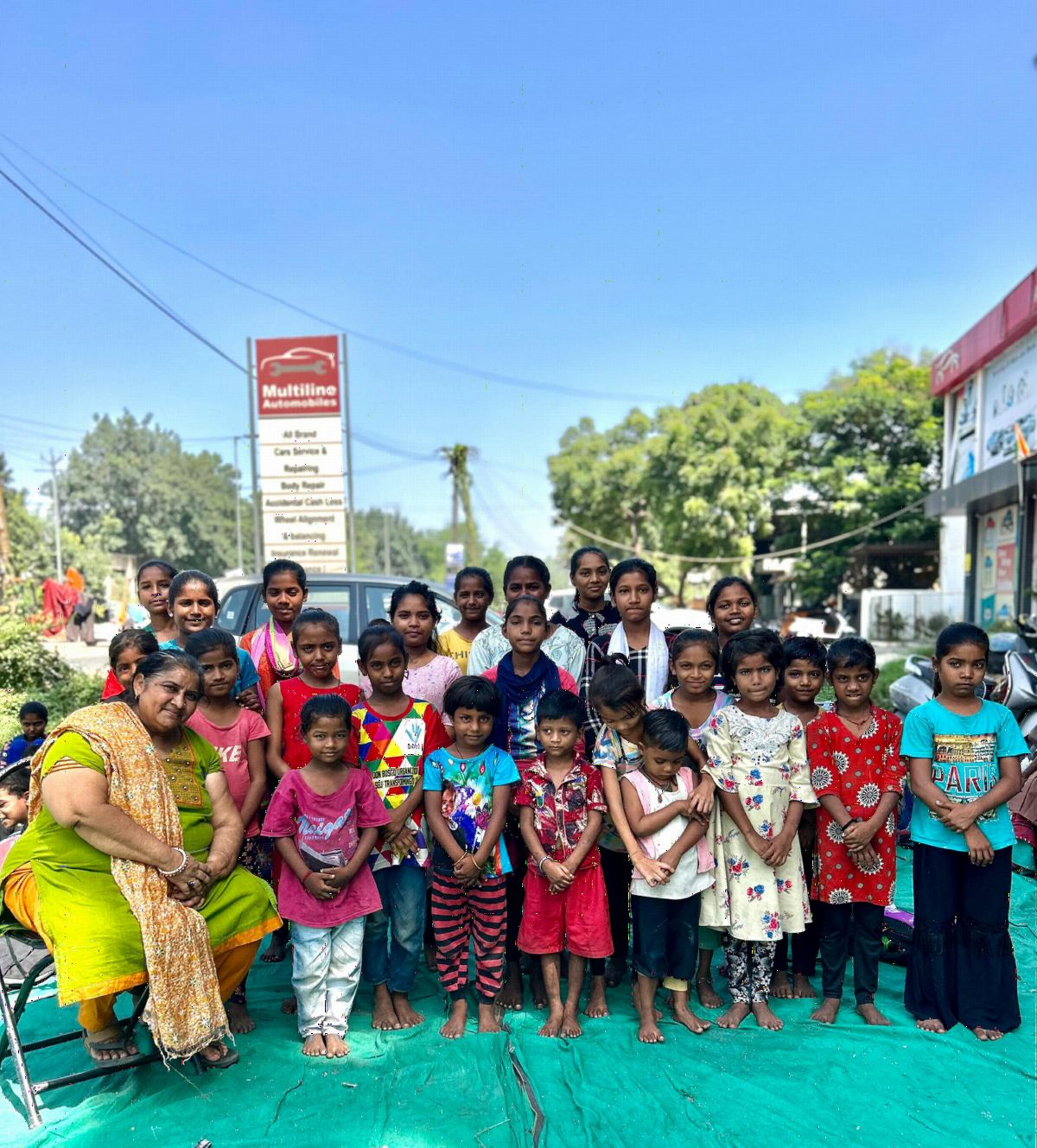 A large group of children and volunteers posing together outdoors.