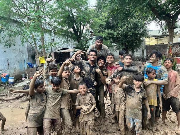 A group of children covered in mud, cheering with raised arms.