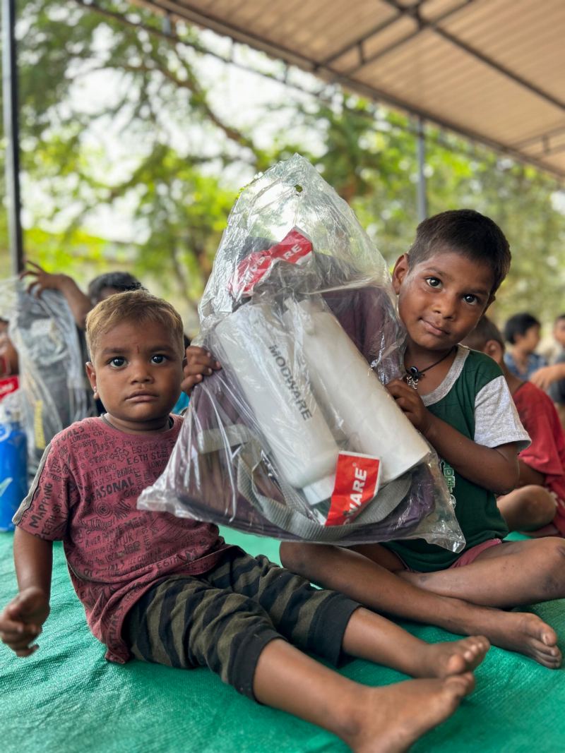 Two young boys smiling and holding a new school kit.