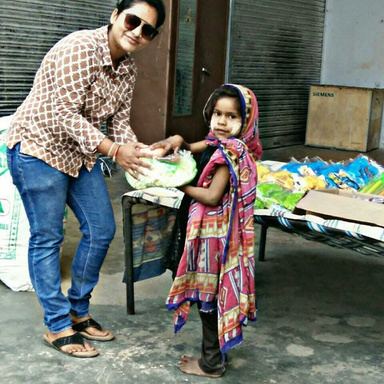 A volunteer handing a kit to a young girl.