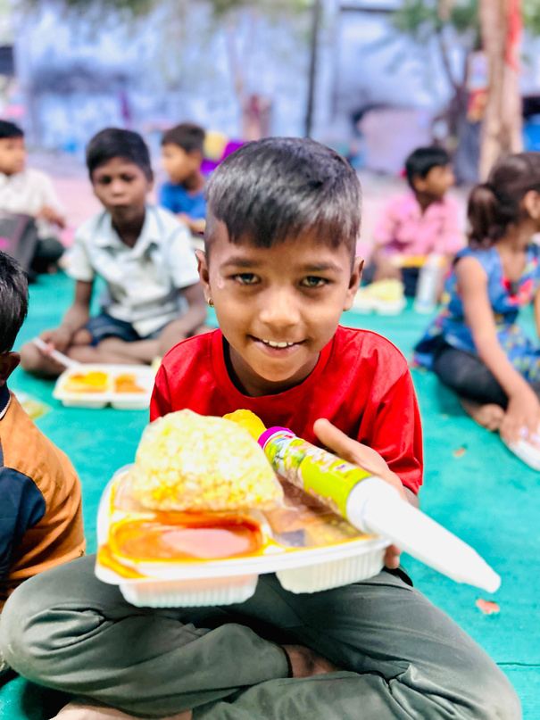A smiling boy holding a meal box.