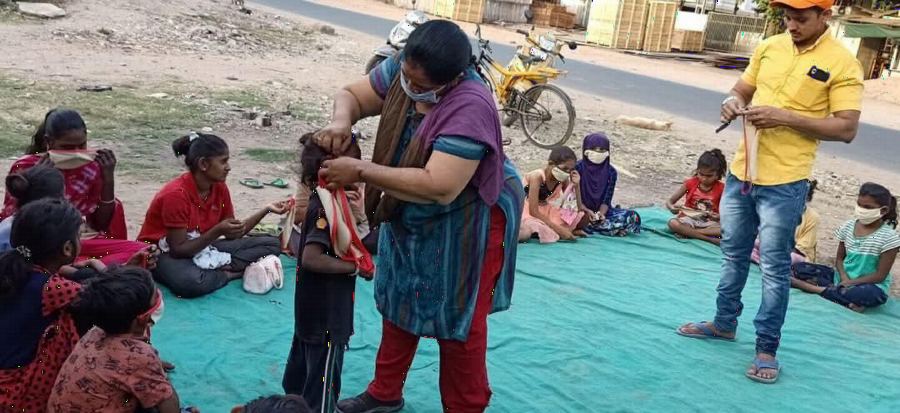 A volunteer helping a child put on a warm sweater.