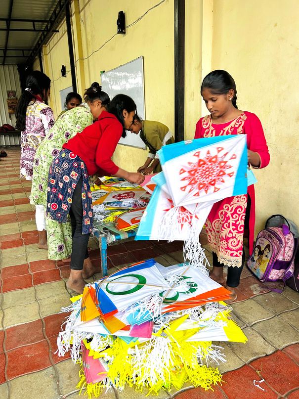 A girl and volunteers handling a colourful kite.