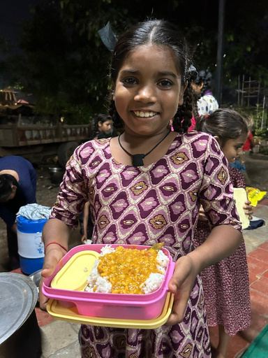 A smiling girl holding a box of healthy food.