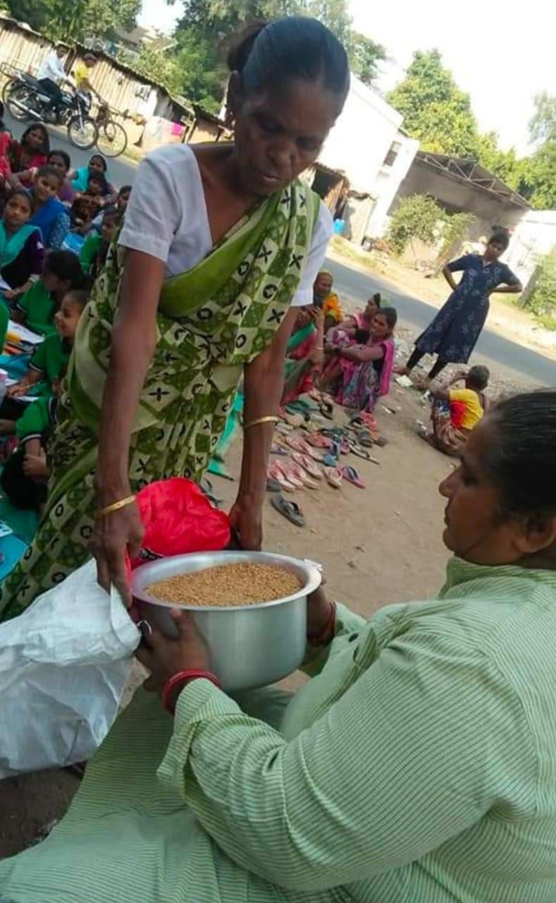 A woman receiving grain from a volunteer during a distribution.