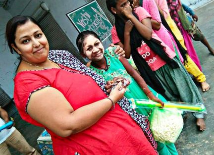 Two smiling women from the foundation with children.